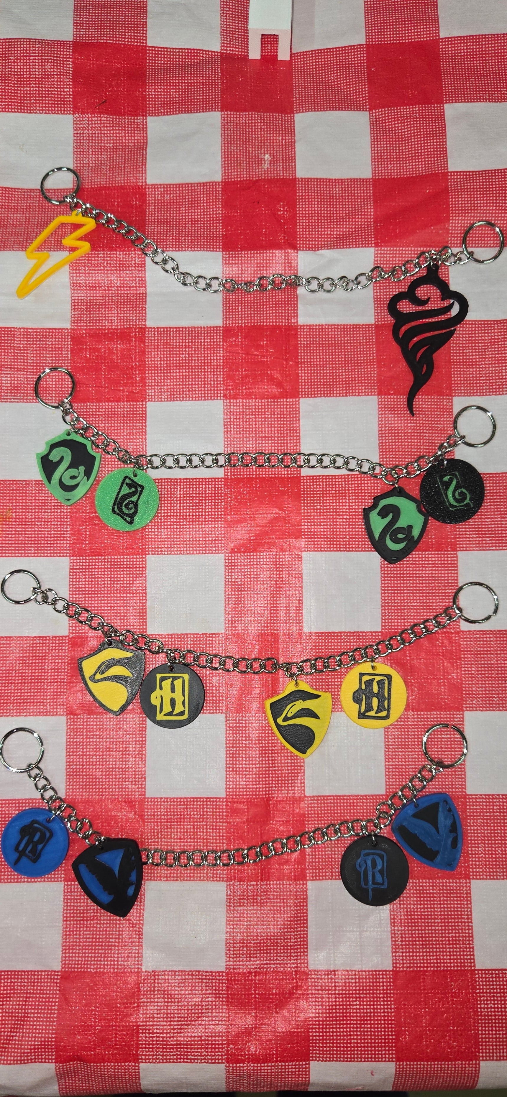 Set of guitar pick holder chains with colorful picks on a red and white checkered tablecloth.